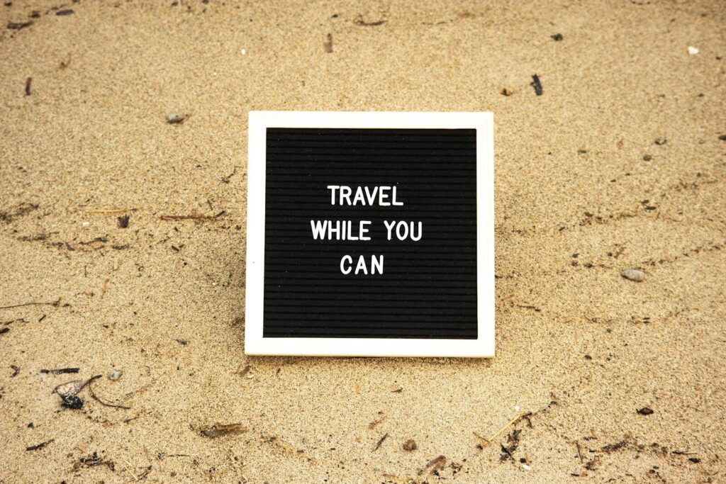 a black and white sign that says travel while you can