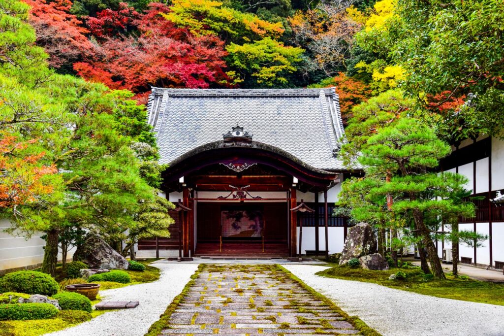 A traditional Japanese temple surrounded by vibrant autumn foliage in a serene garden setting.