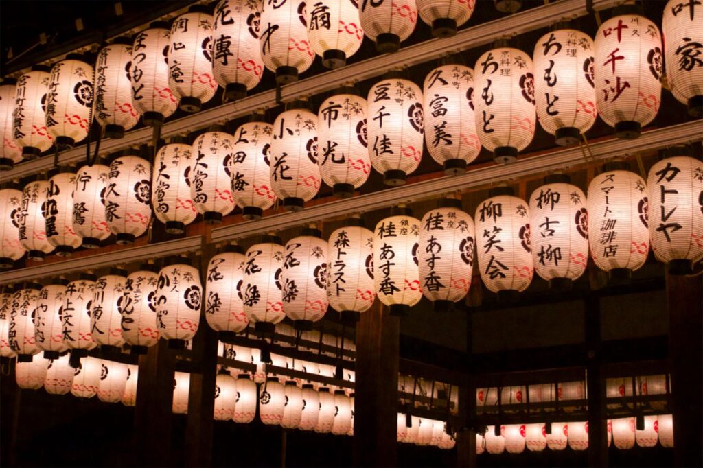 Traditional Japanese lanterns illuminating a temple in Kyoto at night, creating a serene ambiance.